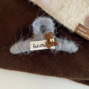 Détail d'une pince à cheveux grise en peluche avec ours et étiquette KokiMo sur tissu