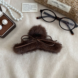 Pince à cheveux marron foncé en fausse fourrure avec nœud sur fond en maille beige