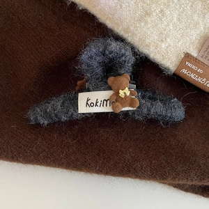 Détail macro d'une pince à cheveux en peluche gris foncé avec un petit ours en 3D