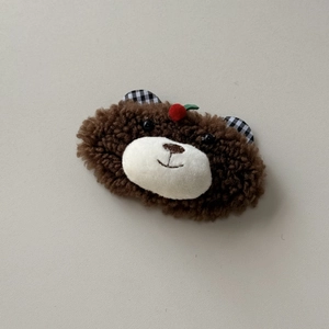 Detailed view of a plush brown bear hair clip with cherry decor and checkered ears