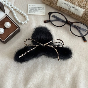 Détail d'une grande pince à cheveux en peluche noire avec nœud à motif léopard