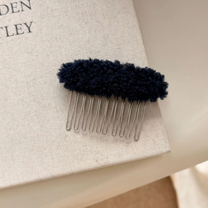 Detail of black faux shearling hair comb with metallic teeth for elegant hairstyling