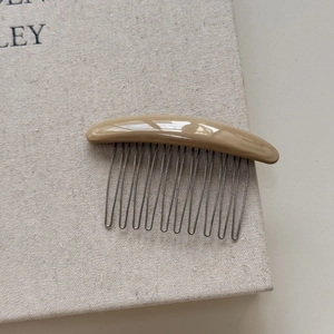 Detail of handmade vintage resin hair comb with engraved logo and silver metal teeth