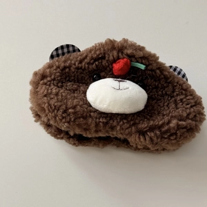 Macro detail of plush brown bear hair clip with lamb wool texture and cherry accent
