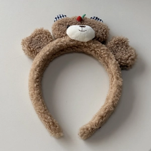 Detail of plush brown teddy bear headband with cherry decor and checkered ears texture