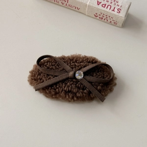 Detailansicht der plüschigen braunen Haarspange mit eleganter Schleife und Strassstein