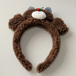 Detailed macro of brown plush teddy bear hairband with cute checkered ears and cherry