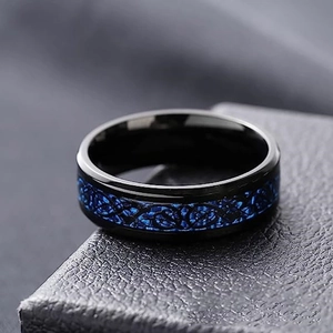 Macro detail of black titanium ring featuring a polished finish and blue Celtic dragon inlay