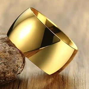 Detailaufnahme des 12mm breiten, gold polierten Titanrings auf Naturstein-Hintergrund