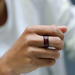 Men's 8mm black titanium ring with red dragon pattern inlay on finger close-up