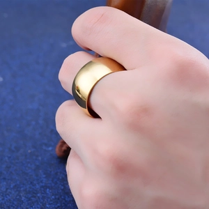 Polierter 12mm breiter goldener Titanring am Finger mit Spiegelreflexionseffekt