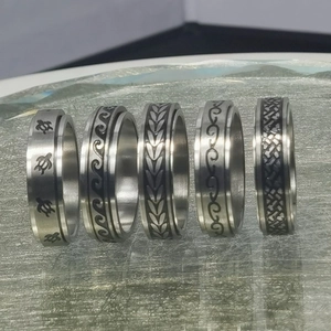 Detalle de cinco anillos giratorios de acero inoxidable con motivos grabados de tortuga