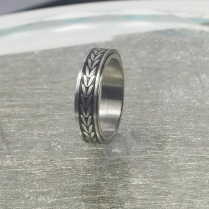 Detalle del anillo giratorio con patrones de trigo plateados sobre fondo negro
