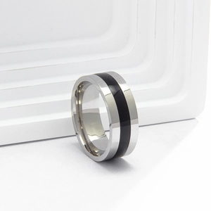 Side view of stainless steel ring with black enamel inlay on white geometric stand