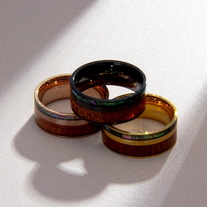 Detailed view of titanium rings featuring walnut wood inlay and colorful abalone shells