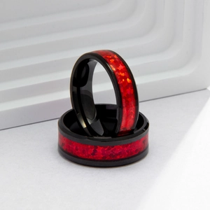 Macro shot of titanium steel rings with inlaid red fire opal and polished black finish
