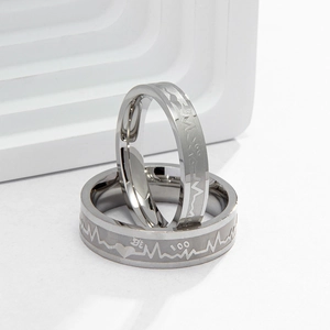 Macro shot of silver stainless steel rings with engraved heartbeat lines and 100 symbol