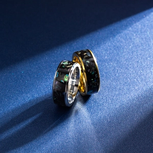 Close-up of titanium steel rings featuring galaxy opal inlay and polished metal edges