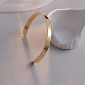 Nahaufnahme eines minimalistischen, vergoldeten Edelstahl-Armreifs mit poliertem Finish