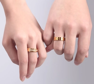 Detail von Titanstahl-Partnerringen in Gold mit Zirkonia-Steinen an einer Hand