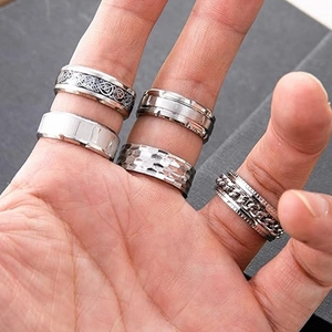 Macro shot of silver stainless steel rings with Celtic knot, frosted, and chain details