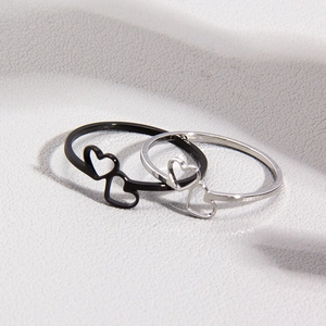 Macro shot of minimalist hollow heart rings in silver and black on grey texture