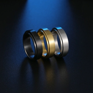 Macro detail of three spinner rings in black gold and silver with matte steel texture