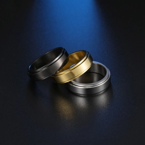 Three-piece 6mm matte band ring set in black, gold, and silver on a dark surface
