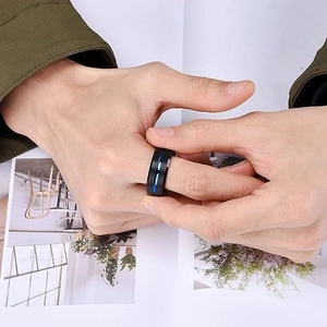 Macro d'une bague noire mate pour homme avec ligne bleue sur le doigt masculin