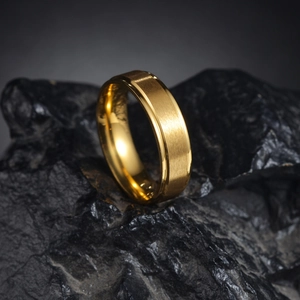 Bague dorée 6mm minimaliste avec finition mate sablée sur présentoir de roche noire