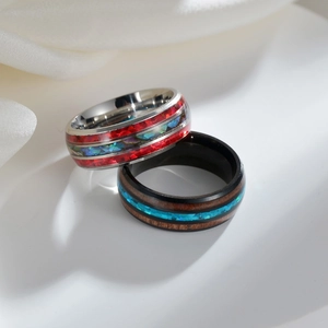 Polished stainless steel rings with colorful opal inlay and dark wood grain texture
