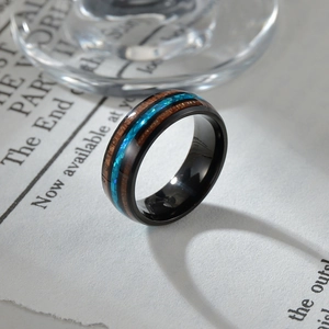 Macro detail of wooden inlay and blue opal crush on black polished ring band