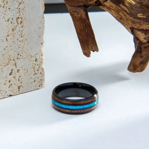 Macro detail of natural wood inlay and blue opal stone on a black metal wedding ring