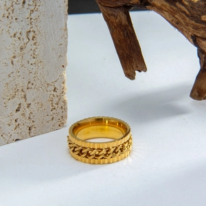 Macro detail of golden rotatable gear ring with chain inlay on natural stone