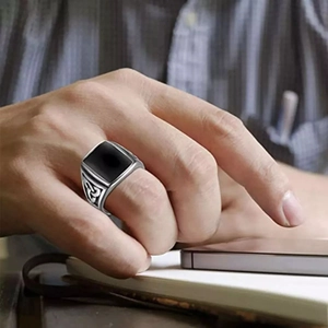 Primo piano dell'anello con sigillo da uomo vintage in acciaio con pietra nera e nodi celtici