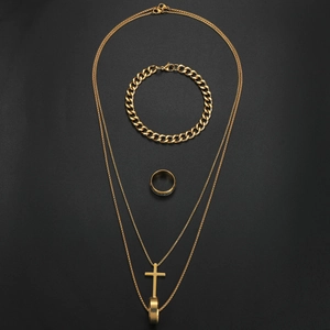 Macro shot of gold cross necklace and Cuban link bracelet jewelry set on black background