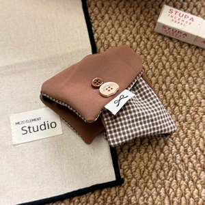 Close-up of brown plaid fabric accessory with Faith & Hope buttons and bow label