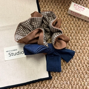 Detailed close-up of brown plaid scrunchie with denim bow on rustic woven mat