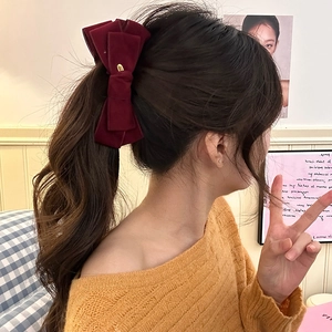 Detailed view of a layered burgundy velvet bow hair clip with gold buckle on a ponytail
