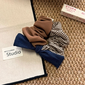 Detailed set of three hair scrunchies featuring brown stripes, plaid, and a navy denim bow