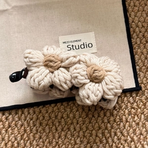 Detail of handmade crochet flower banana hair clip on beige canvas and woven carpet