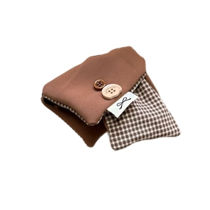 Brown plaid fabric pouch with buttons and woven label on a clean white background