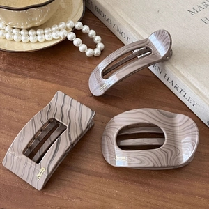 Retro faux wood grain acetate hair claws in geometric shapes on a vintage wooden surface