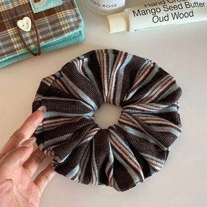 Detail of a large knitted stripe scrunchie in coffee, blue, and pink retro vintage patterns
