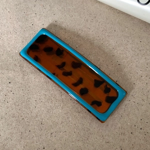 Detail of teal and tortoiseshell wavy hair clip in a minimalist rectangle shape
