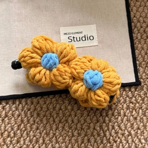 Detail of handmade crocheted sunflower banana hair clip with vibrant yellow and blue yarn