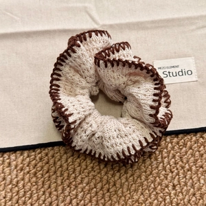 Detail of French vintage knit scrunchie with beige wool texture and brown wavy edges