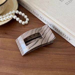 Detailed close-up of marble pattern hair claw clip with gold Barrette France lettering