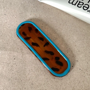 Detail of tortoise shell hair clip with vibrant sky blue border on textured background