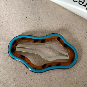 Macro view of wave-shaped hair clip with blue border and leopard print pattern